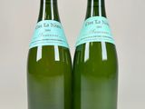 two bottles of green wine with labels on them sitting next to each other