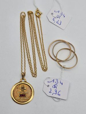 un gros plan sur un collier en or et deux bagues posés sur une table