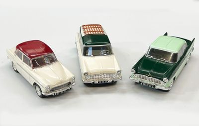 trois petites voitures assises l'une à côté de l'autre sur une surface blanche