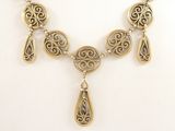 Ce collier est en métal doré et comporte un grand pendentif orné de larmes suspendues.
