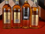 four bottles of wine are lined up on a red cloth