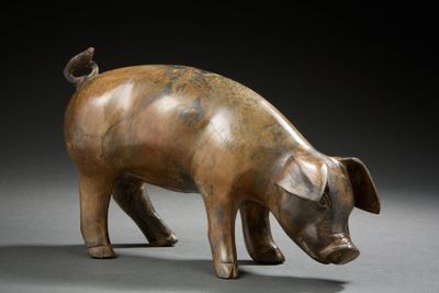 bronze sculpture of a pig on a gray surface