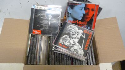 une boîte remplie de CD et des CD posés sur une table
