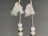 necklace with white beads and tassels on a black surface