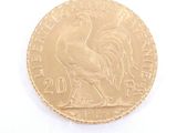 a gold coin with a rooster on it on a white surface