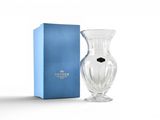 le vase en verre se trouve à côté d'une boîte bleue, posée sur une surface blanche