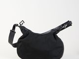 le sac noir est posé sur une surface blanche et est muni d'une bandoulière noire