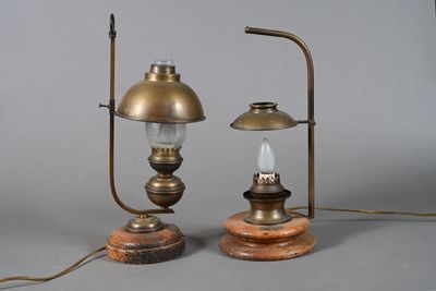 une paire de lampes à huile anciennes en laiton, posées sur des socles en bois, sur fond gris