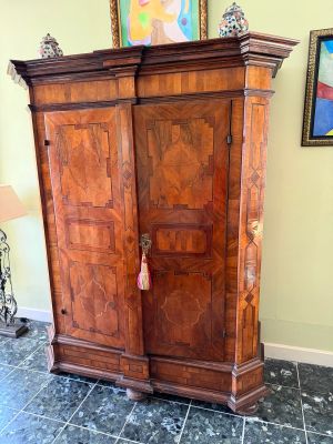 a large wooden armoire in a room with a painting on the wall
