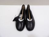 pair of black leather shoes with a bow on top of a white surface
