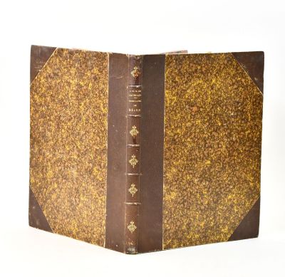 an old book with a brown cover sitting on top of a white surface
