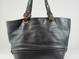 a person holding a black leather tote bag on a white background