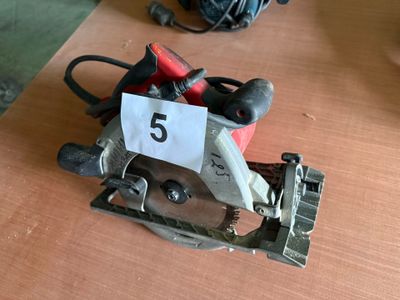 une petite scie circulaire posée sur une table sur laquelle est inscrit le chiffre 5