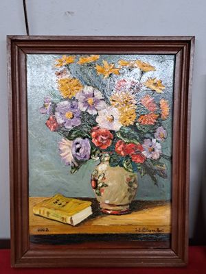 un tableau représentant des fleurs dans un vase et un livre posé sur une table