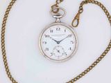 a silver pocket watch with a chain on a white surface