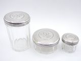 three glass jars with silver lids on a white surface