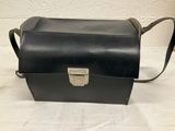 a black leather bag with a metal handle on a white surface