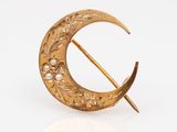 an image of a gold broochle with pearls on it