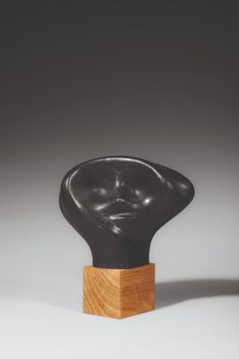 une photo d'une sculpture représentant une tête posée sur un socle en bois