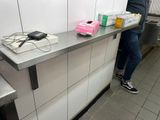 une personne debout devant un comptoir, tenant une boîte de nourriture