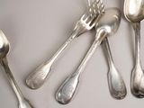 five silver spoons and two silver spoons on a table