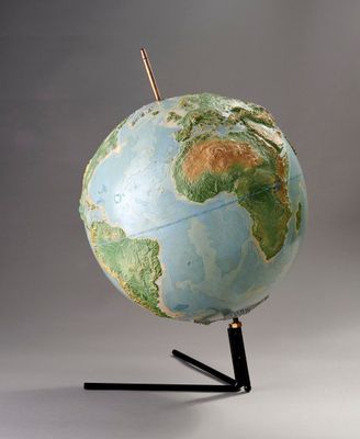 un globe bleu et vert posé sur un socle noir