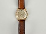 a close up of a watch on a white surface with a brown strap