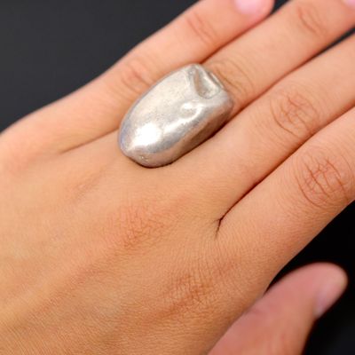 a woman ' s hand with a silver ring on it