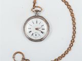 an old pocket watch with a chain around it on a white surface