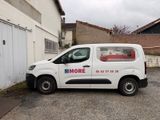 une petite camionnette blanche garée devant un bâtiment