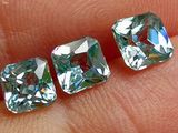 trois diamants de couleur aigue-marine, taille carrée, au doigt d'une personne