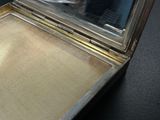 a silver case with a mirror on a black surface