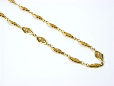 gros plan d'un collier en or avec une chaîne sur une surface blanche