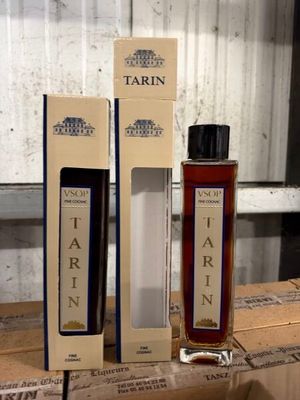 two bottles of tarin sit on a wooden table next to boxes