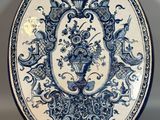 une assiette bleue et blanche richement décorée, ornée d'un motif floral