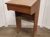 a small wooden desk with a drawer on top of it