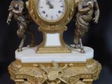 a gold clock with angels on it on a black background