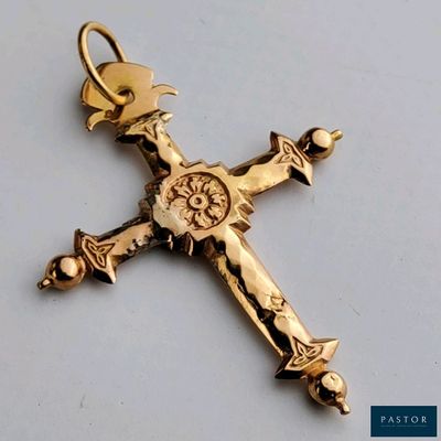 une croix en or surmontée d'une couronne, posée sur une table