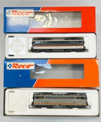 trois cartons contenant des trains miniatures posés sur une table