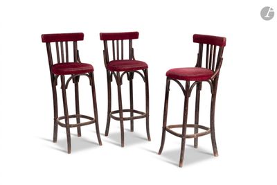 trois tabourets de bar rouges placés les uns à côté des autres sur une surface blanche