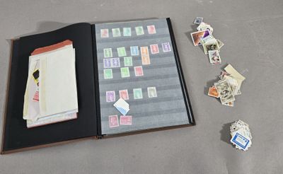 un livre ouvert sur lequel sont collés des timbres et un tas de timbres éparpillés sur le sol
