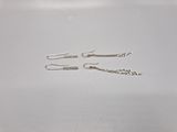 Deux paires de boucles d'oreilles en argent sont posées sur une surface blanche.