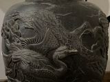 a black vase with a dragon on it sitting on a table