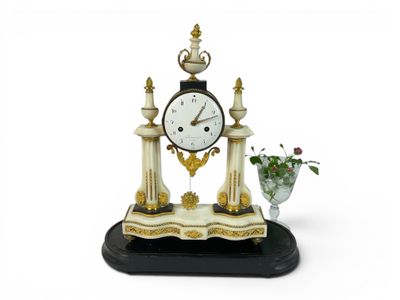 a clock that is sitting on a table with a vase of flowers