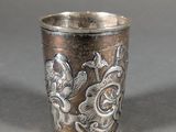 a silver cup sitting on a table with a bird on it