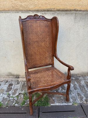 une chaise en bois posée sur un trottoir, près d'un mur
