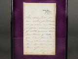 an old letter is displayed in a purple frame on a gray surface