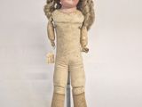 an old doll with blonde hair is standing on a metal stand