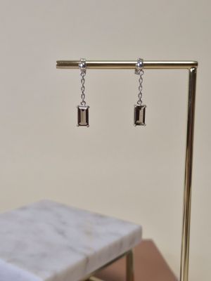 a pair of earrings hanging from a stand on a table