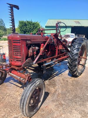a red tractor that is parked in the dirt